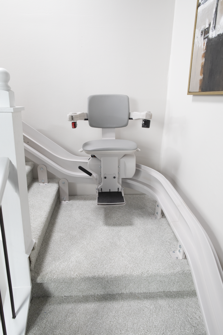The Bruno Elite Curved stairlift installed on a white staircase, with the chair midway between the top and bottom of the stairs.