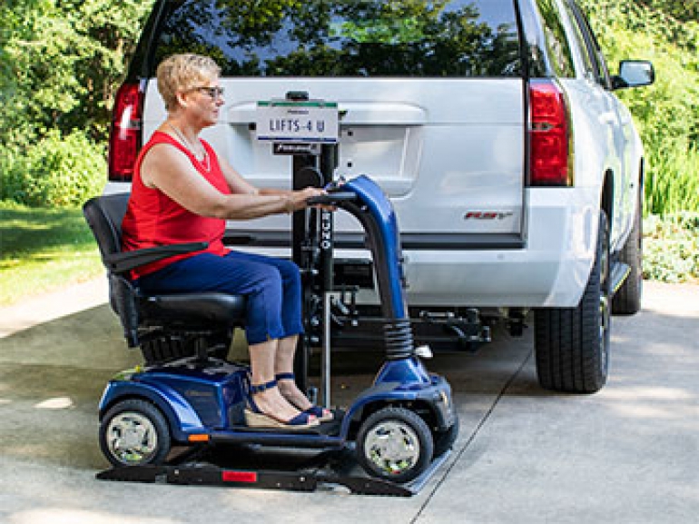 A woman sits on her scooter after having driven onto her Out-Sider scooter lift