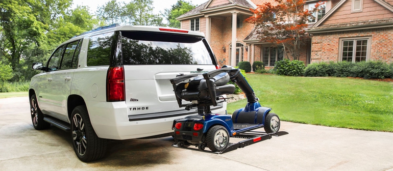 An Out-Sider scooter lift is lifted on the back of a SUV