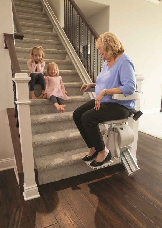 Elan Straight Stairlift, woman sitting on chair while grandkids sit on the stairs.