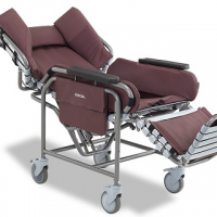 The Broda Centric positioning wheelchair with burgundy padding, shown in a reclined position with the footrest extended. thumbnail