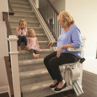 Elan Straight Stairlift, woman sitting on chair while grandkids sit on the stairs.