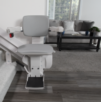 The chair of the Elite indoor curved stairlift at the bottom of a staircase, with a tidy living room in the background thumbnail