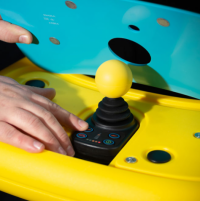 A close up of the Explorer Mini tray, with the top cover lifted up to show the full joystick below. The cover is turquoise and the joystick knob is bright yellow. thumbnail