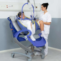 A woman is being lifted with assistance from a nurse using a Maxi Sky 2 ceiling lift. thumbnail