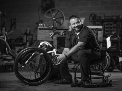 An NSM Service Tech smiles while repairing a manual wheelchair